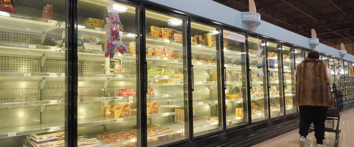 A shopper walks past partially empty frozen food coolers at a grocery in Cranberry Township, Pa., on Tuesday, Jan. 11, 2022. (AP Photo/Gene J. Puskar)